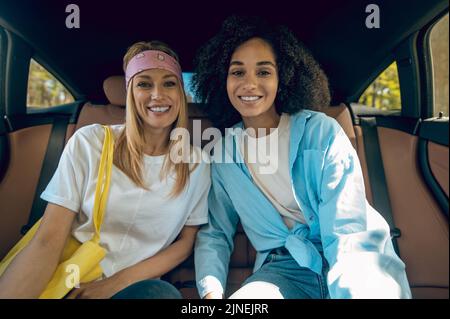 Zwei niedliche junge Frauen sitzen im Auto Stockfoto