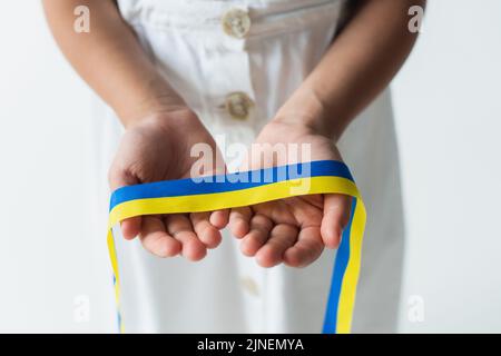 Beschnittene Ansicht der verschwommenen Mädchen hält blau und gelb Band isoliert auf grau, Stock Bild Stockfoto