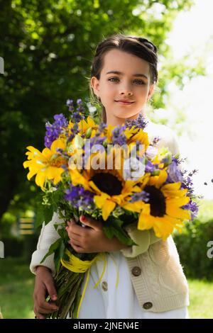 Patriotische Mädchen mit blauen und gelben Strauß Blick auf Kamera im Freien, Stock Bild Stockfoto