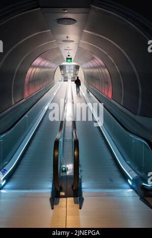 Eine Person, die mit einem Silhouetten umhergeht, der auf einem Reisefahrtreppen oder einer Rolltreppe in einem Tunnel bei South Eveleigh in Sydney, Australien, läuft Stockfoto