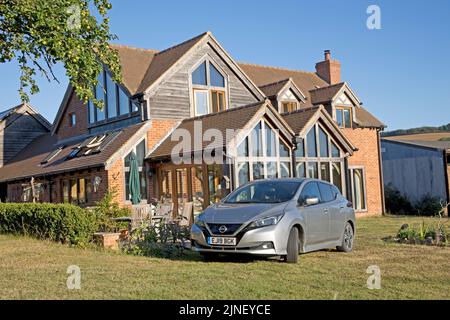 Metallisch graues Nissan Leaf e-connecta EV-Elektroauto, das vor dem Ökohaus Cotswolds in Großbritannien geparkt ist Stockfoto