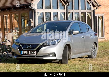 Metallisch graues Nissan Leaf e-connecta EV-Elektroauto, das vor dem Ökohaus Cotswolds in Großbritannien geparkt ist Stockfoto