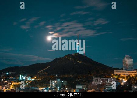 Seoul N Tower auf dem Namsan Berg bei Nacht mit hellem Vollmond Stockfoto