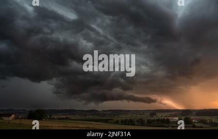 Blitzeinschlag und Gewitterwolken während des Sommergewitters bei Sonnenuntergang in der Nähe von Schaffhausen, Schweiz Stockfoto