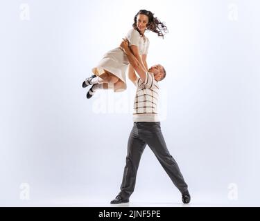 Erstaunt junge tanzende Mann und Frau tanzen Sport Tänze isoliert auf weißem Hintergrund. 50s, 60s ,70s amerikanischer Mode-Stil. Stockfoto