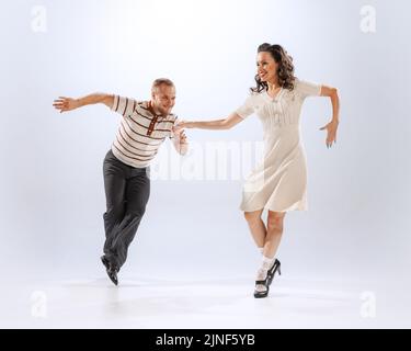 Erstaunt junge tanzende Mann und Frau tanzen Sport Tänze isoliert auf weißem Hintergrund. 50s, 60s ,70s amerikanischer Mode-Stil. Stockfoto