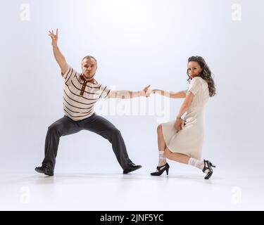 Dynamisches Porträt von emotionalen Mann und Frau tanzen Sporttänze isoliert auf weißem Hintergrund. 50s, 60s ,70s amerikanischer Mode-Stil. Stockfoto