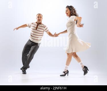 Erstaunt junge tanzende Mann und Frau tanzen Sport Tänze isoliert auf weißem Hintergrund. 50s, 60s ,70s amerikanischer Mode-Stil. Stockfoto