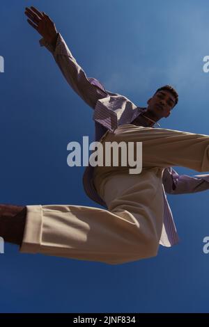 Bottom view of african american man in white Pants Springen unter blauem Himmel, Stock image Stockfoto