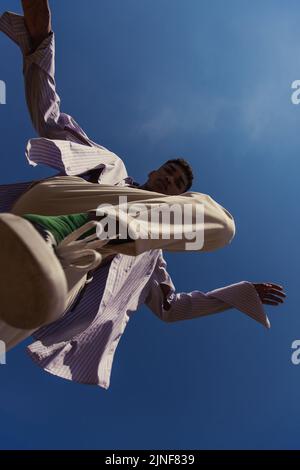 Bottom view of african american man in trendy Kleidung unter blauem und klarem Himmel, Stock Bild Stockfoto