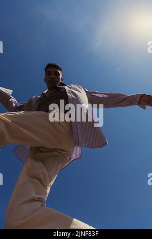 Bottom view of african american man in trendy Kleidung unter blauem und klarem Himmel, Stock Bild Stockfoto