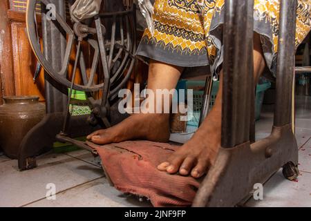Nahaufnahme der Beine einer Frau bei der Arbeit an einer alten mechanischen Nähmaschine Stockfoto