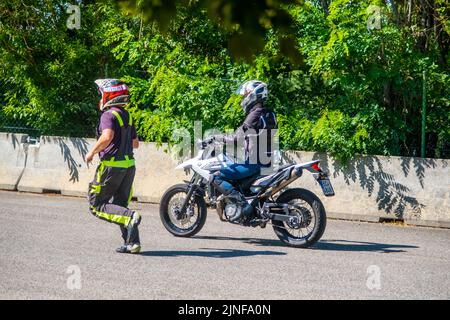 Prag, Tschechische Republik - 12. Juli 2022: Männlicher Instruktor kontrolliert den L-Fahrer, während sie im Geschicklichkeitstraining Motordrome Fahrrad fährt Stockfoto