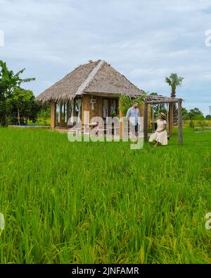 Paar Männer und Frauen im Urlaub in einer Gastfamilie in Thailand, Öko-Farm mit grünem Reisfeld während der Monsunsaison in Thailand Stockfoto