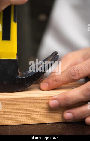 Beschnittene Ansicht des Mannes, der Nagel mit Art und Weise in der Nähe von Holzbrett aufnahm, Stockbild Stockfoto