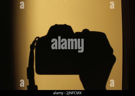 Silhouette einer Hand, die eine Kamera hält. Konzept für Überwachung, Fotografie, Kunst, Künstler, Beobachten Stockfoto