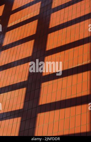 Roter Ziegel mit Gitterschatten auf der Oberseite. Hintergrundtapeten-Konzept für moderne Gebäude, hart arbeitend, abstrakte, urbane Räume Stockfoto