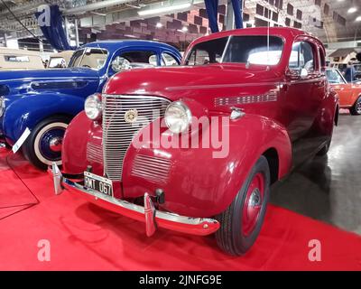 Altes rotes Chevrolet Chevy Master Coupé 1939 von GM. Ausstellungshalle. Vorderansicht. Chrom. Kühlergrill. Oldtimer-Show. Stockfoto