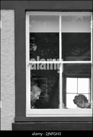 Mann und Frau sitzen beim Lesen im Fenster der Hütte Stockfoto