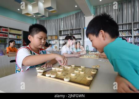 (220811) -- HEFEI, 11. August 2022 (Xinhua) -- Schüler lernen chinesisches Schach in Hefei, Ostchinas Provinz Anhui, 11. August 2022. Einige Schulen in Hefei bieten in diesem Sommer kostenlose Kindertagesstätten für Schüler an. Die Kindertagesstätten helfen nicht nur, die Sommerzeit der Schüler zu bereichern, sondern auch, den Druck auf berufstätige Eltern zu lockern, die sich sonst während der Ferien um ihre Kinder kümmern müssen. (Xinhua/Zhou Mu) Stockfoto