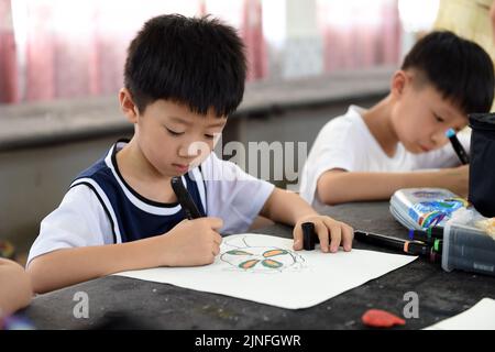 (220811) -- HEFEI, 11. August 2022 (Xinhua) -- Schüler lernen Malerei in Hefei, Ostchina, Provinz Anhui, 11. August 2022. Einige Schulen in Hefei bieten in diesem Sommer kostenlose Kindertagesstätten für Schüler an. Die Kindertagesstätten helfen nicht nur, die Sommerzeit der Schüler zu bereichern, sondern auch, den Druck auf berufstätige Eltern zu lockern, die sich sonst während der Ferien um ihre Kinder kümmern müssen. (Xinhua/Zhou Mu) Stockfoto