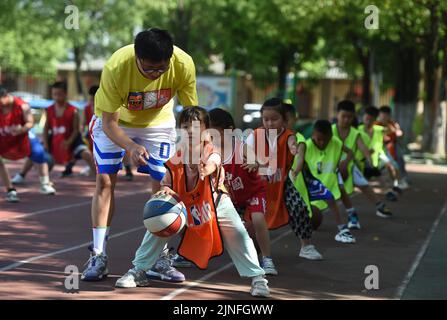 (220811) -- HEFEI, 11. August 2022 (Xinhua) -- Schüler lernen Basketball in Hefei, der ostchinesischen Provinz Anhui, zu spielen, 11. August 2022. Einige Schulen in Hefei bieten in diesem Sommer kostenlose Kindertagesstätten für Schüler an. Die Kindertagesstätten helfen nicht nur, die Sommerzeit der Schüler zu bereichern, sondern auch, den Druck auf berufstätige Eltern zu lockern, die sich sonst während der Ferien um ihre Kinder kümmern müssen. (Xinhua/Zhou Mu) Stockfoto