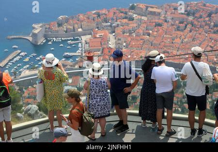 Zahlreiche Touristen kommen mit der Seilbahn auf den Srdj Hügel, wo sie am 11. August 2022 einen schönen Blick auf Dubrovnik, Kroatien, genießen. Stockfoto