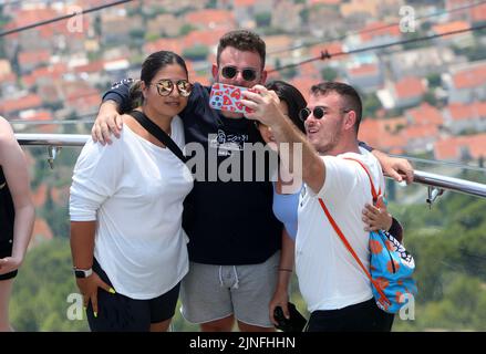 Zahlreiche Touristen kommen mit der Seilbahn auf den Srdj Hügel, wo sie am 11. August 2022 einen schönen Blick auf Dubrovnik, Kroatien, genießen. Stockfoto