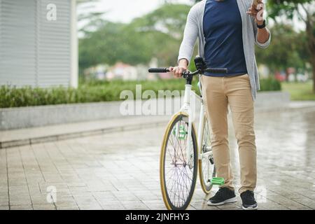 Zugeschnittenes Bild eines Radfahrers, der auf seinem Smartphone Nachrichten abcheckt Stockfoto