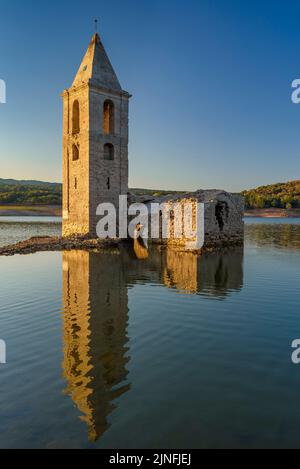 Sonnenaufgang am Glockenturm von Sant Romà de Sau und dem Stausee Sau während der Sommertrockenheit von 2022 (Osona, Barcelona, Katalonien, Spanien) Stockfoto