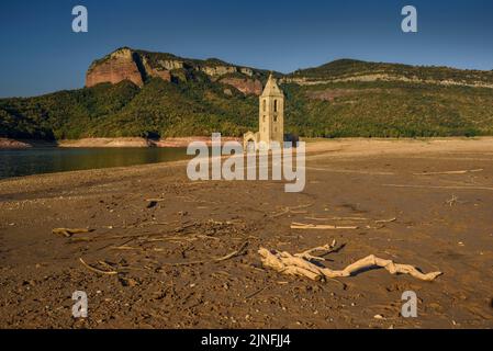 Sonnenaufgang am Glockenturm von Sant Romà de Sau und dem Stausee Sau während der Sommertrockenheit von 2022 (Osona, Barcelona, Katalonien, Spanien) Stockfoto