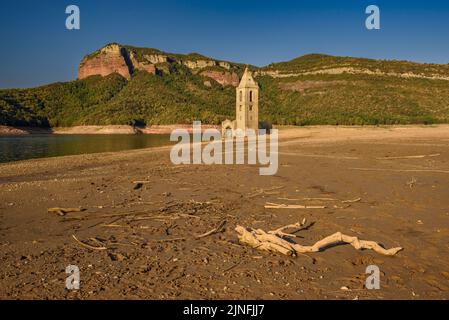 Sonnenaufgang am Glockenturm von Sant Romà de Sau und dem Stausee Sau während der Sommertrockenheit von 2022 (Osona, Barcelona, Katalonien, Spanien) Stockfoto