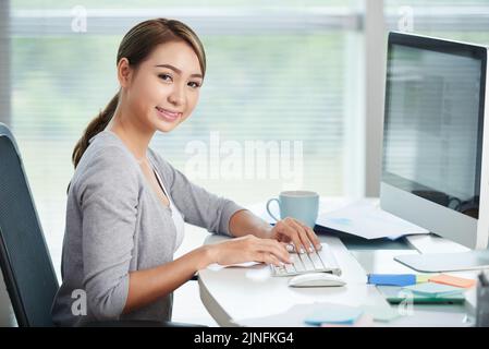 Fröhliche junge Unternehmerin, die am Computer arbeitet Stockfoto