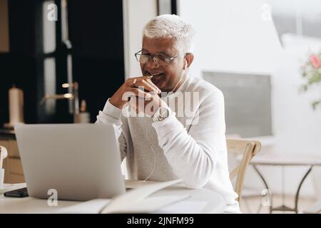 Glücklicher Geschäftsmann, der an einem Online-Meeting in seinem Heimbüro teilnimmt. Ein reifer Geschäftsmann, der während der Arbeit eine Videokonferenz mit seinen Kollegen führt Stockfoto