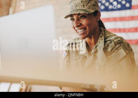 Fröhliche Soldatin, die fröhlich lächelt, während sie mit ihrer Familie auf einem Laptop chattet. Amerikanische Militärangehörige, die mit ihren Angehörigen kommuniziert, jammern Stockfoto