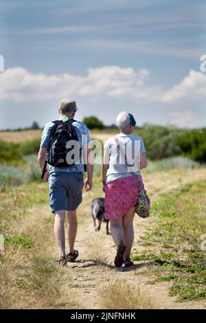 Ältere Rentnerpaar zu Fuß mit Hund entlang der Küste Weg steif Norden norfolk england Stockfoto