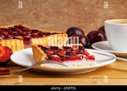 Nahaufnahme Stück hausgemachten Pflaumenkuchen und Tasse Kaffee auf Holztisch. Geringer Fokus. Stockfoto