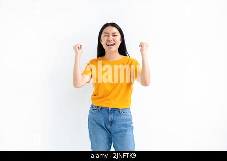 Fröhliche asiatische Frau jubelt sagen ja glücklich schauen und den Sieg über weißem Hintergrund zu feiern Stockfoto
