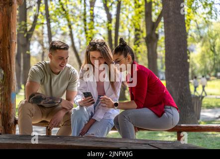 Freundschaft, Technologie und internationales Konzept - Gruppe von Freunden mit Smartphones im Sommerpark Stockfoto