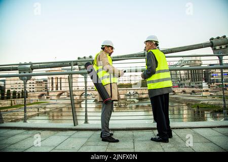 Zwei leitende Bauleiter stehen während des Gesprächs auf der Brücke Stockfoto