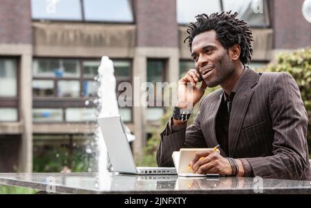 Arbeiten Im Freien. Ein junger Londoner Business-Profi, der gerne außerhalb des Büros arbeitet. Aus einer Serie von verwandten Bildern mit demselben Modell. Stockfoto