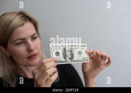 Kontrollleuchte für gefälschte Geldfälschungen. 100 Dollar gegen das Fenster in seiner Hand. Überprüfen Sie für Wasserzeichen auf hundert Dollar-Schein. Transluzenz der Stockfoto
