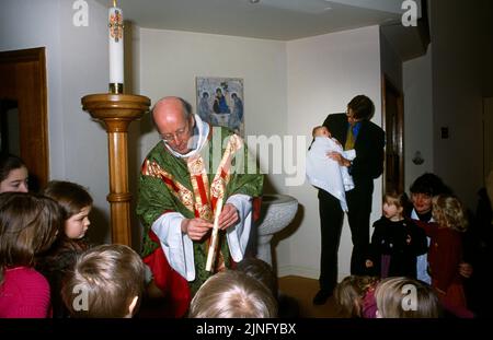 Priester zeigt Kinder Pashal Kerze bei der Taufe in St. Bernard's Catholic Church Surrey England Stockfoto