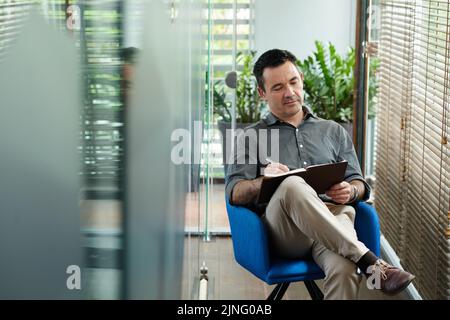 Inspirierter Mann, der Gedanken und Ideen in sein Tagebuch schrieb Stockfoto