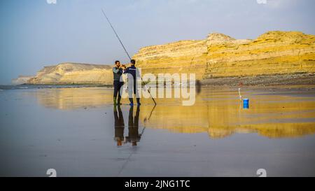 Laayoune, Marokko - 30. Juli 2022 : zwei Fischer und seine Angelrute Stockfoto