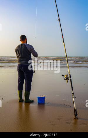 Laayoune, Marokko - 30. Juli 2022: Ein Fischer und seine Fischerstange Stockfoto