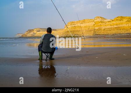 Laayoune, Marokko - 30. Juli 2022 : Ein Fischer hält und seine Angelrute Stockfoto