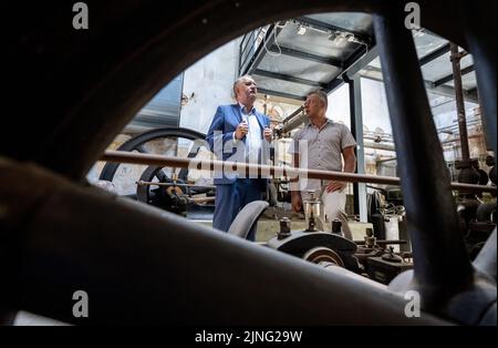 11. August 2022, Sachsen, Stollberg: Der sächsische Staatsminister für Landesentwicklung, Thomas Schmidt (CDU, l.), und der Bürgermeister der Stadt Stollberg, Marcel Schmidt (Freie Wähler), sprechen im Alten Schlachthaus in Stollberg zwischen historischen Kühlmaschinen. Das Industriegebäude wird heute als Veranstaltungsort für Konzerte, Workshops und Projekte genutzt. Die Stadt, die rund 11.500 Einwohner hat und an der Autobahn 72 liegt, hat viele Beispiele dafür, wie Millionen von Bundes- und Landesmitteln für den Bau neuer Gebäude oder die Renovierung alter Gebäude und ihre Nutzung genutzt wurden. Seit Beginn Stockfoto