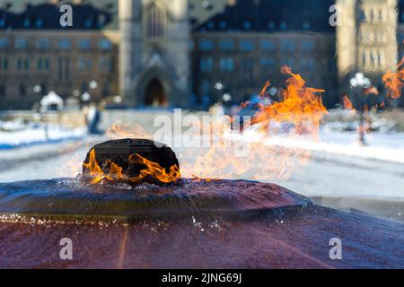 Die ewige Flamme brennt vor einem schneebedeckten kanadischen Parlamentsgebäude in Ottawa, Ontario. Es erinnert an den 100.. Jahrestag der Confed Stockfoto