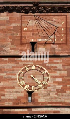 Sonnenuhr und mechanische Uhr am Basler Dom, die in verschiedenen Epochen gebaut wurden und die Tradition der Schweiz bewahrten Stockfoto